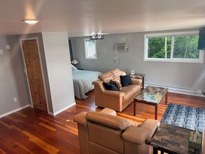 A living room with a sofa, a coffee table, and a window with a view of trees.