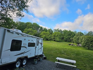 A recreational vehicle (RV) parked in a grassy area with a picnic table nearby.