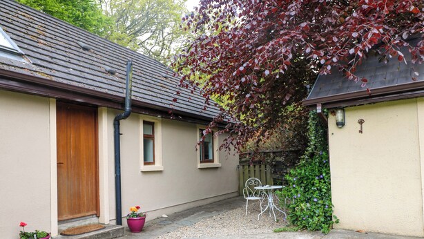 Ein Haus mit Tür, Fenstern, einer kleinen Terrasse und einem Garten.