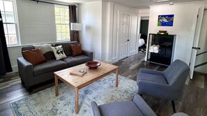 A modern living room with a sofa, a coffee table, and a chair. - Historic Bruce House | Hot Tub, Fire Pit &AC (Shelburne)