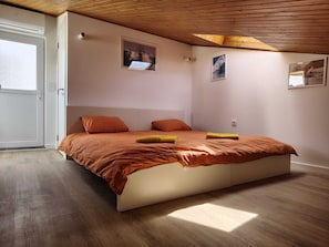 Ein Schlafzimmer mit einem Bett, Holzboden und einer Tür.