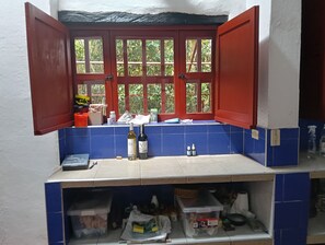 Eine Küche mit Fenster, blauen Fliesen und verschiedenen Küchengegenständen auf der Arbeitsplatte.