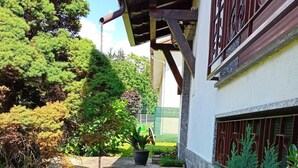 Puutarhapolku johtaa rakennukseen, jossa on puinen pergola ja metallinen portti.