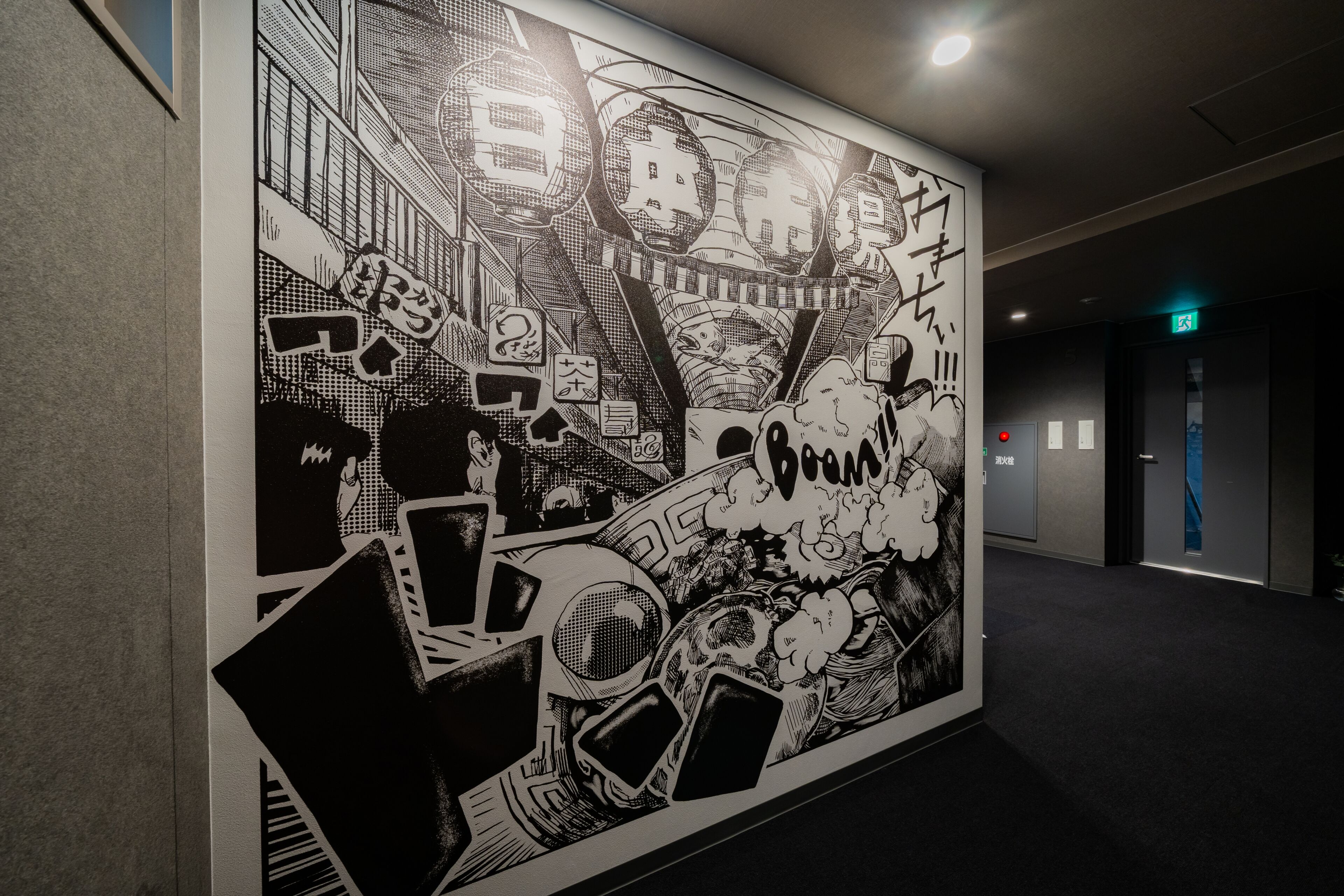 A hallway with a large black and white mural on the wall depicting a chaotic scene with buildings and explosions.