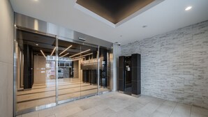 En modern hotellentrén med en glasfasad, en stenmur och en skylt med texten ”HOTEL LEGAL”.