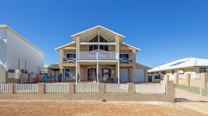 A two-story house with a balcony, a garage, and a fenced yard. - JBay Hideaway: 4  BR, 2  BA House in Jurien Bay, Sleeps 8 (Jurien Bay)