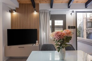 Ein modernes Wohnzimmer mit Fernseher, einem Esstisch und einem Blumenstrauß.