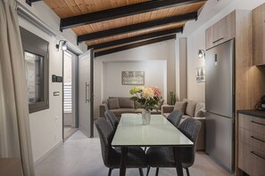 Eine moderne Küche mit Esstisch, Stühlen, einem Kühlschrank und einer Couch.