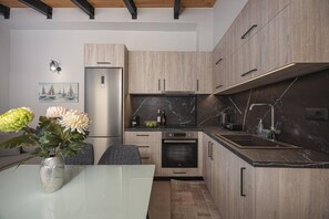 Eine moderne Küche mit Holzschränken, einem Edelstahlkühlschrank, einem eingebauten Backofen und einer Marmor-Spritzschutzwand.
