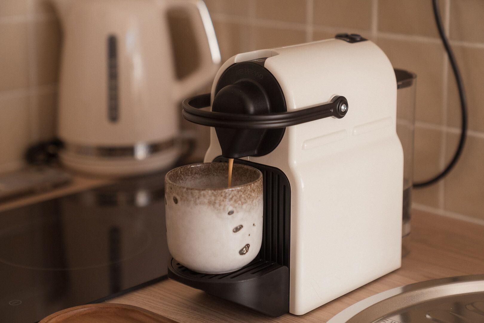 Una cafetera amb una tassa al peu, connectada a una presa d'electricitat.