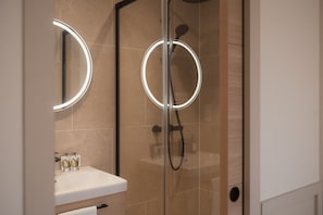 Une salle de bain moderne avec une douche à parois de verre, un meuble-lavabo avec un miroir et un évier.