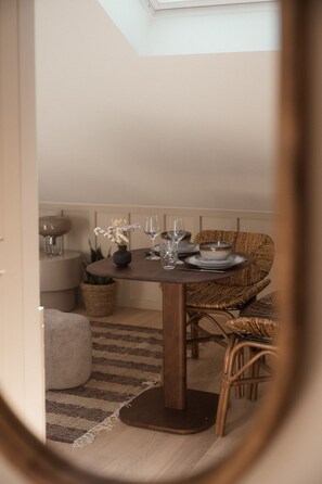 A dining area with a round table, wicker chairs, and a small side table with a vase and glasses. - Apparts RennesBnB Duhamel (Rennes)