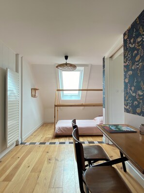 Ein Zimmer mit einem Etagenbett, einem Schreibtisch mit Stuhl, einem Fenster und einer Heizung.