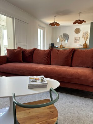 A living room with a brown sofa, a white table, and a green chair. - 1930s house, ideal for families, close to beaches (Plounéour-Brignogan-plages)