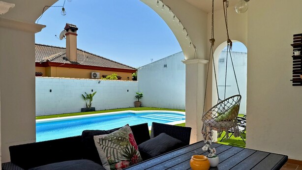 A patio with a pool, outdoor seating, hanging lights, and a hanging chair. - Villa Valdeazahares - Ole Solutions (Puerto de Santa María)
