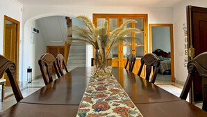 A dining room with a long table, chairs, a ceiling fan, and a decorative plant. - Villa Valdeazahares - Ole Solutions (Puerto de Santa María)