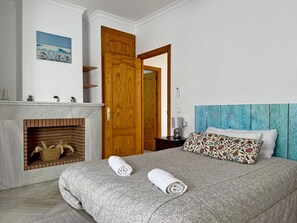 Ein Schlafzimmer mit Bett, einer Holztür, einem Kamin und einem an der Wand hängenden Bild.