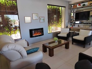 Un salon avec une cheminée, un canapé, une table basse et un téléviseur.