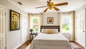 A bedroom with a bed, a ceiling fan, a window with curtains, a framed picture on the wall, and a nightstand with a lamp. - FIFA26 Chic Suite - Near NRG  (Houston)