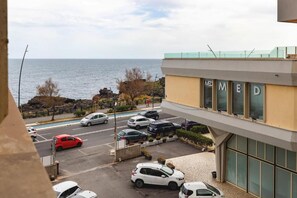 Ein Gebäude mit 'MED' auf den Fenstern, ein Parkplatz mit Autos und Blick aufs Meer.