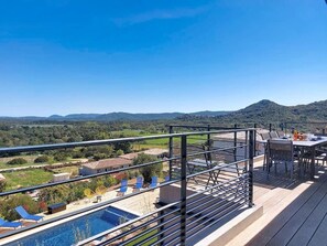 Eine Dachterrasse mit Pool, Sitzgelegenheiten im Freien und Blick auf die Landschaft.