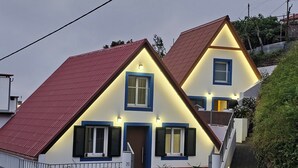 A two-story house with a red roof, white walls, and blue window frames. - Grandfather's House (Santana)