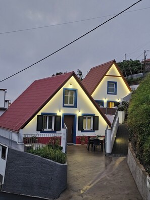 A two-story house with a red roof, white walls, and blue window frames. - Grandfather's House (Santana)