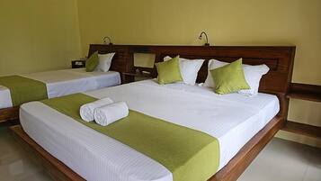 A hotel room with two beds, each with a wooden headboard, white bedding, and green throw pillows.