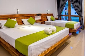 Habitación de hotel con dos camas, cada una con cabecero de madera, ropa de cama blanca y detalles en verde.