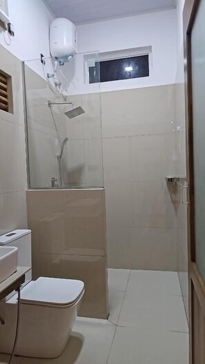 Un baño con ducha, inodoro y una ventana pequeña.