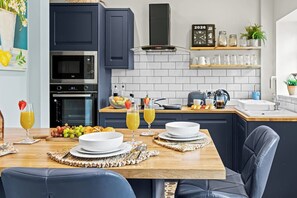 A modern kitchen with dark cabinets, a microwave, oven, and a clock displaying 2026. - Perfect Home for Trades or Small Families (Greater Manchester)