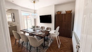 A dining area with a wooden table, chairs, and a TV mounted on the wall. - Contractor, Families, Free Parking, Private Garden (Worsley)