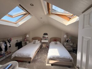 Ein Schlafzimmer mit zwei Betten, einem Schreibtisch, einem Kleiderschrank und Dachfenstern.