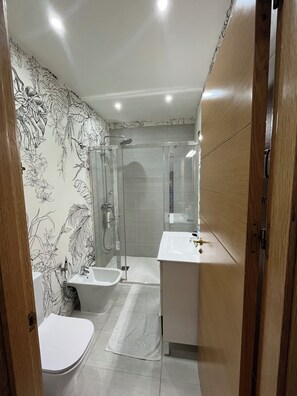 Un baño moderno con ducha, inodoro y lavamanos.