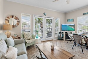 Ein Wohnzimmer mit Sofa, Couchtisch, Fernseher und Essbereich mit Stühlen.