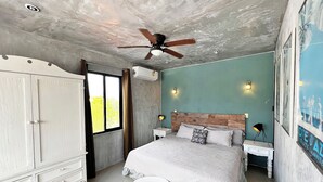 Ein Schlafzimmer mit Bett, Kleiderschrank, Deckenventilator, Klimaanlage und einem fenster mit Vorhängen.