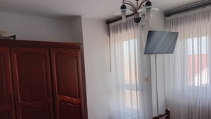 Una camera da letto con un armadio in legno, un letto con copriletto fantasia, una ventola a soffitto e tende trasparenti.