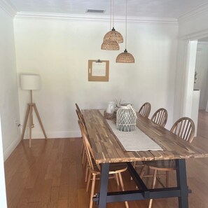 Un coin repas avec une table en bois, des chaises, des lampes en osier suspendues au plafond et un certificat encadré accroché au mur.