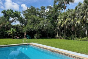 En pool med rutsjebane, omgivet af frodig vegetation og palmer.