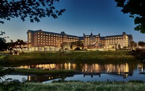 Un grand hôtel à plusieurs étages, avec un bassin d’eau aux reflets changeants à l’avant et une pelouse bien entretenue.