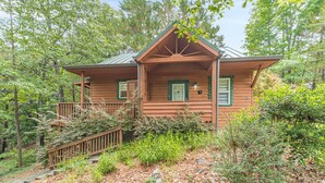 A wooden cabin with a porch, surrounded by dense forest. - Heart of Helen Cabin (Helen)