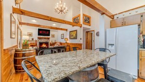 A kitchen with a stone countertop, wooden beams, a fireplace, and a white refrigerator. - Heart of Helen Cabin (Helen)