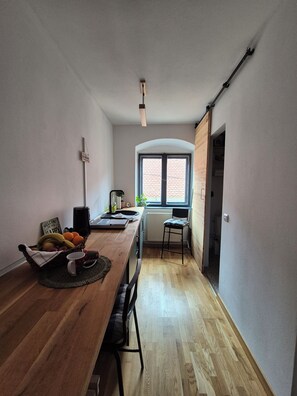 Ein Essbereich mit einem Holztisch, Stühlen, einem Obstkorb, einer kleinen Pflanze und einem Fenster mit Blick.