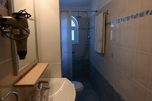 Et badeværelse med bruser, toilet, håndvask og håndklædestang.