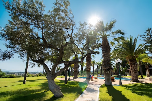 A pathway leading to a pool area surrounded by trees and a clear sky.