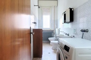 Un bagno compatto con lavatrice, toilette e lavandino.