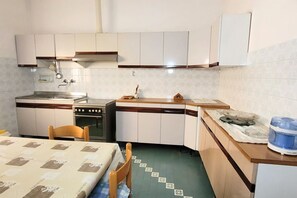 Una cocina pequeña con gabinetes blancos, una estufa y un lavamanos.