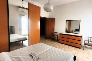 Een slaapkamer met een bed, een kaptafel, een stoel en een spiegel.