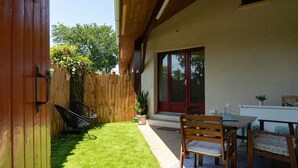 A patio with a wooden table and chairs, a small garden, and a sliding glass door. - Villa Patio Léon & Gustave - Quiet & walking distance (Vieux-Boucau-les-Bains)