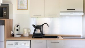A modern kitchen with white cabinets, a Bosch dishwasher, a coffee maker, and a black electric kettle. - Villa Patio Léon & Gustave - Quiet & walking distance (Vieux-Boucau-les-Bains)